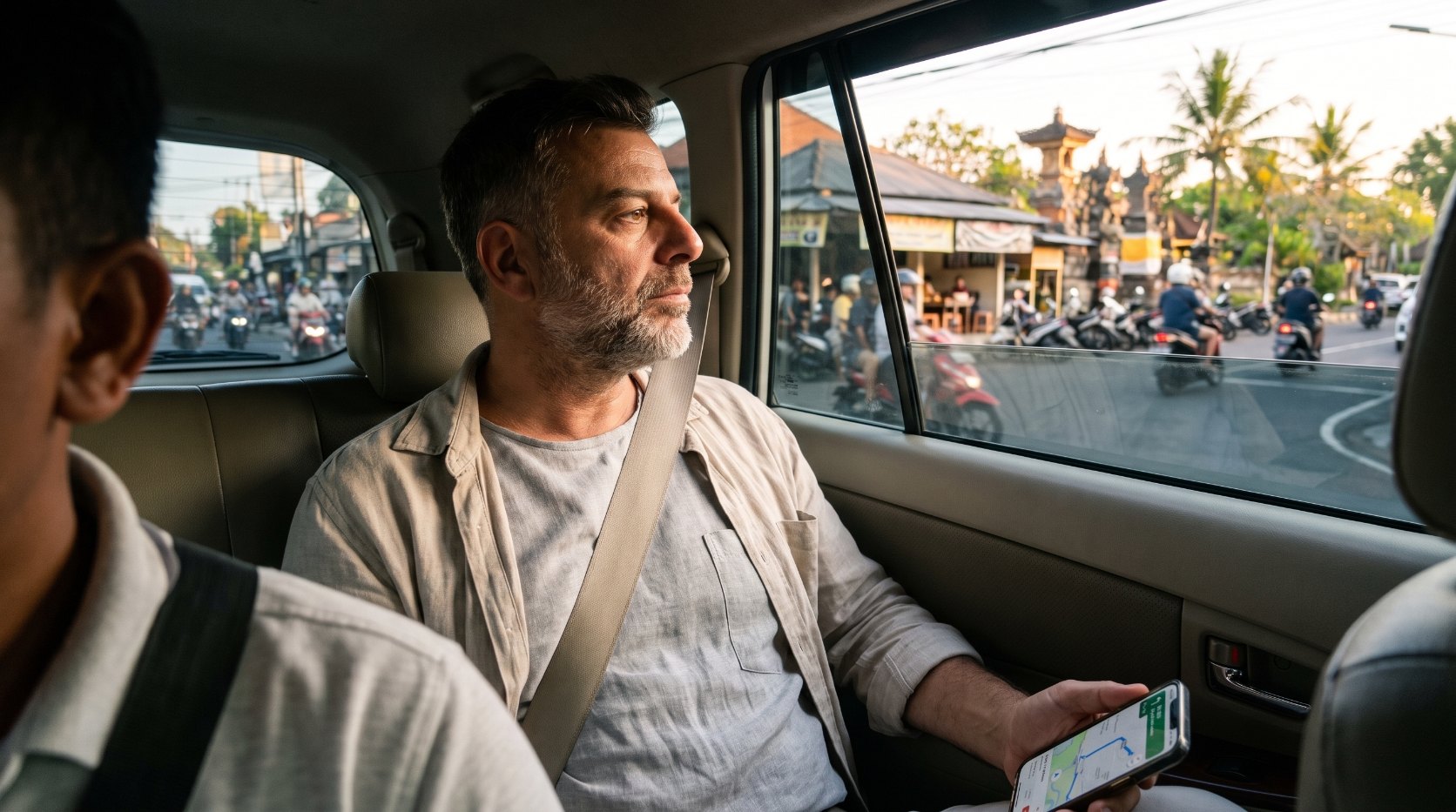 Emre Konuralp in the back seat of a car looking out at Bali traffic on the way to his accommodation — AI editorial illustration